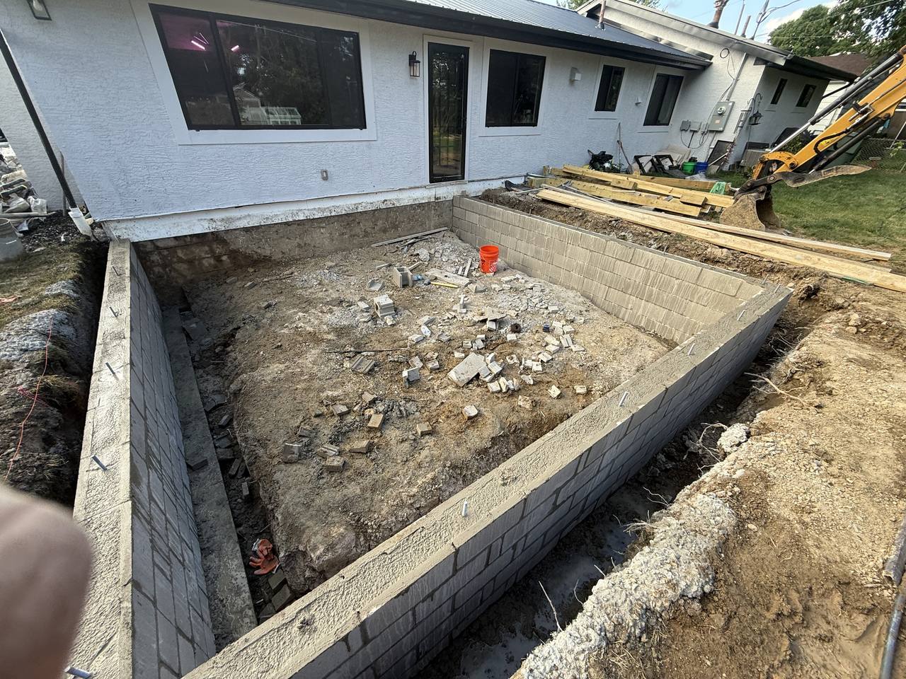 CMU block foundation wall for a home addition with excavation equipment on site