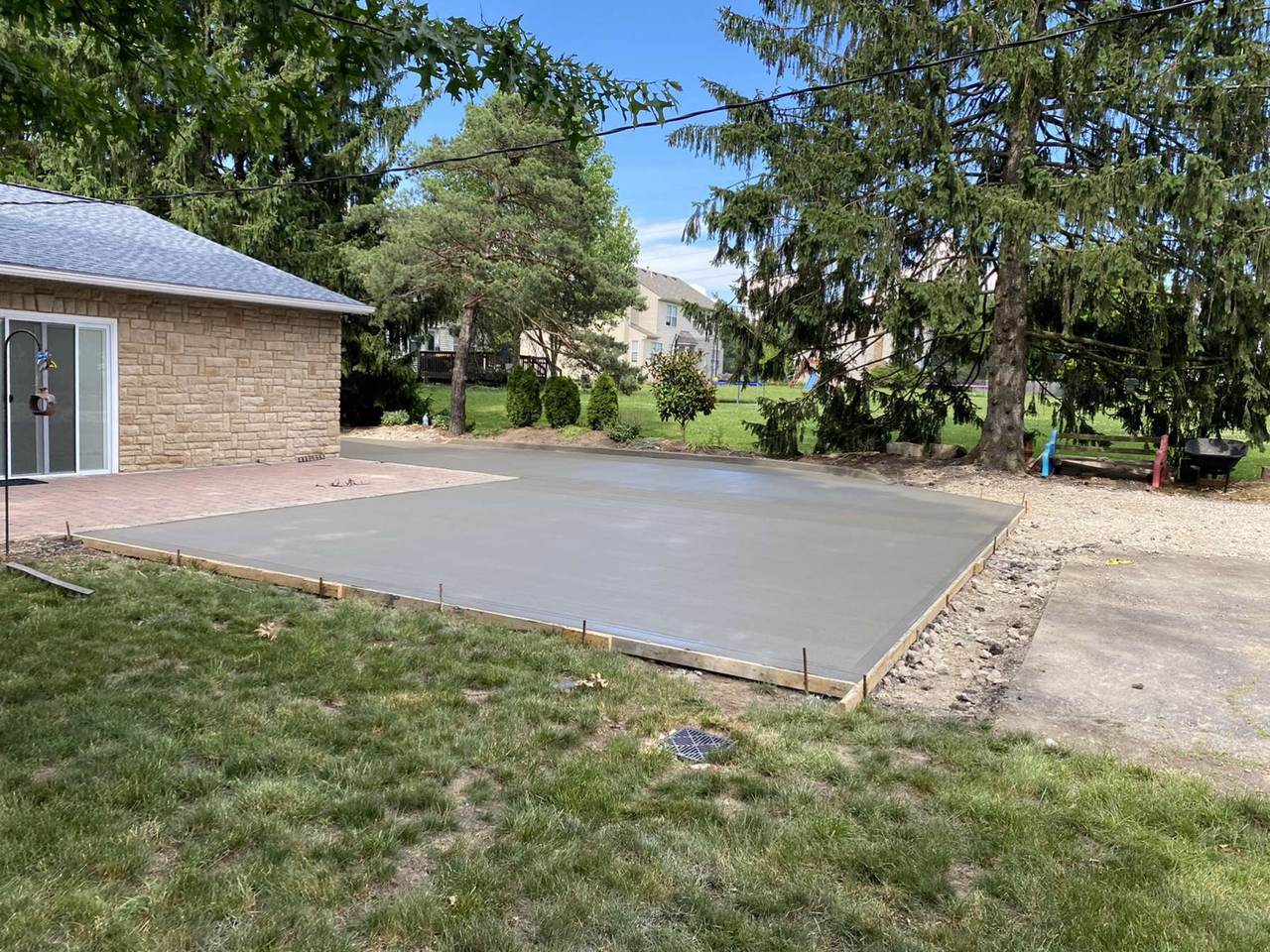 Concrete patio paired with an existing paver patio in a backyard